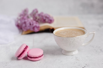 a sprig of lilac and macaroni, an old book, lie on a light gray background. Greeting card. Space for text