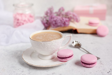 A Cup of morning coffee, a bowl of lilac, macaroni, on a light background. Postcard good morning