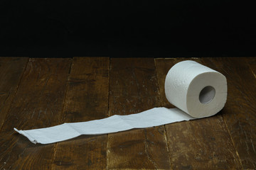 A roll of toilet paper lies on a wooden table