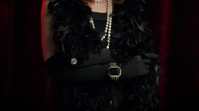 Woman dressed in Roaring twenties era demonstrates jewelry and bijouterie of that time on hands and dress. Flappers, retro fashion, vintage lady costume