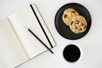 cup of hot black coffee on white table background with notebook and stationery.  Work from home concept.