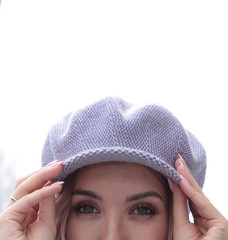 Beautiful green eyes close-up. Spring 2020 fashion and outfit. Girl in a cap. Close-up look. Hands at the visor. Magical eyes. Insightful look. White background.