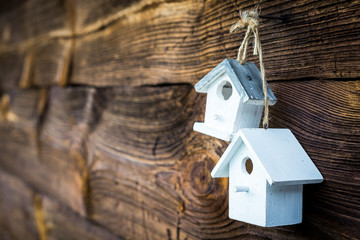 Little white birdhouses hanging on a nail. Hand made decorations on aged wood texture background