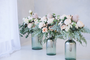 Beautiful and stylish artificial flowers in a glass vases stand on a floor. Flower decor on a white background