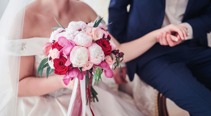 Obraz na płótnie Canvas Beautiful peonies wedding bouquet. White pions and bright roses in the bride 's bouquet. Bride holds bouquet of flowers