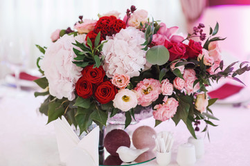 Wedding table decor with red flowers. Beautiful bouquet of fresh flowers in the vase