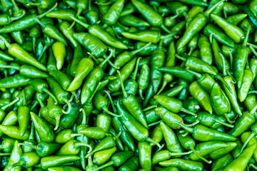 Close up of green chili peppers. Top view of raw green peppers at street food market. Vegetable background