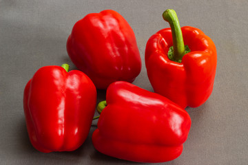 Close-up of four red peppers on a gray tablecloth 