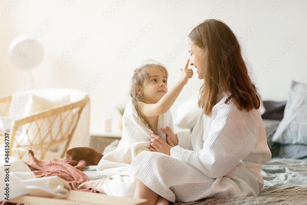 Wall mural Daughter and mother in playful mood sitting on bed  in bedroom after shower. 