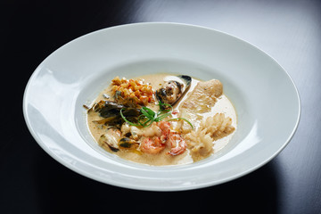 Plate of seafood in sauce on table.