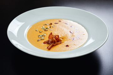 Cream soup with bacon and pumpkin seeds.