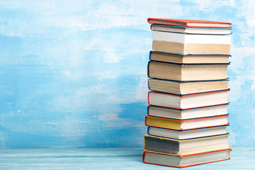 Composition with vintage old hardback books, diary, fanned pages on wooden deck table and red background. Books stacking. Back to school. Copy Space. Education background.