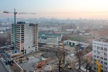 Building crane and buildings under construction against evening sky. Construction site, city at sunrise, Kyiv skyline