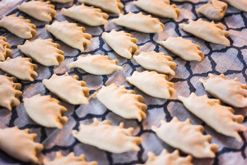Traditional Polish home made dumplings on kitchen cloth - pierogi made of dough. Preparing meal at home. Pierogi ruskie, lots of raw dumplings