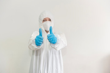 Doctor in white protective suit, medical mask and blue gloves shows a thumbs up. Epidemic, pandemic of coronavirus covid 19. Copy Space