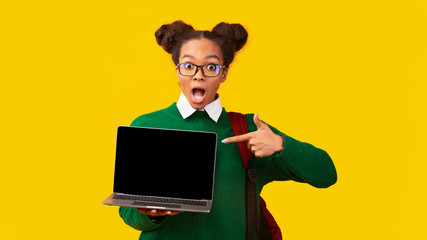 Happy afro girl pointing at blank laptop screen
