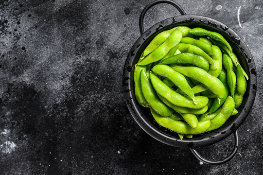 Raw beans edamame in the colander. Black background. Top view. Copy space