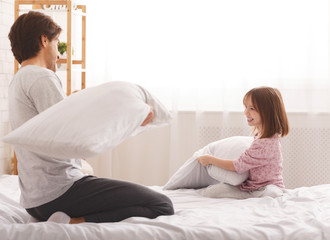 Funny father and daughter playing with pillows