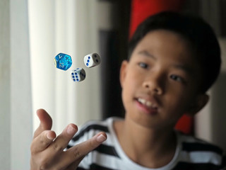 Closeup of an Asian boy throwing the dices up into the air. Selected focus.