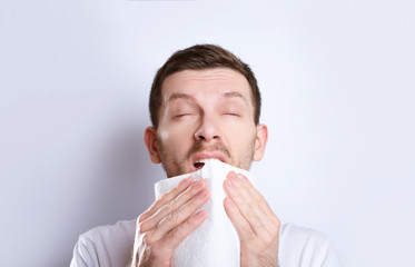 cold guy sneezes into a napkin