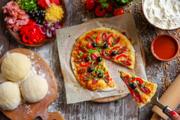 From above unrecognizable woman holding a piece of tasty pizza. Horizontal indoors shot.