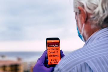 Covid-19 pandemic, global emergency, senior man receives a message on his cell phone on phase 1. Stay at home to avoid contagion by coronavirus
