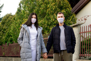Man and woman in a protective mask. A woman is standing on the street. Holding hands.