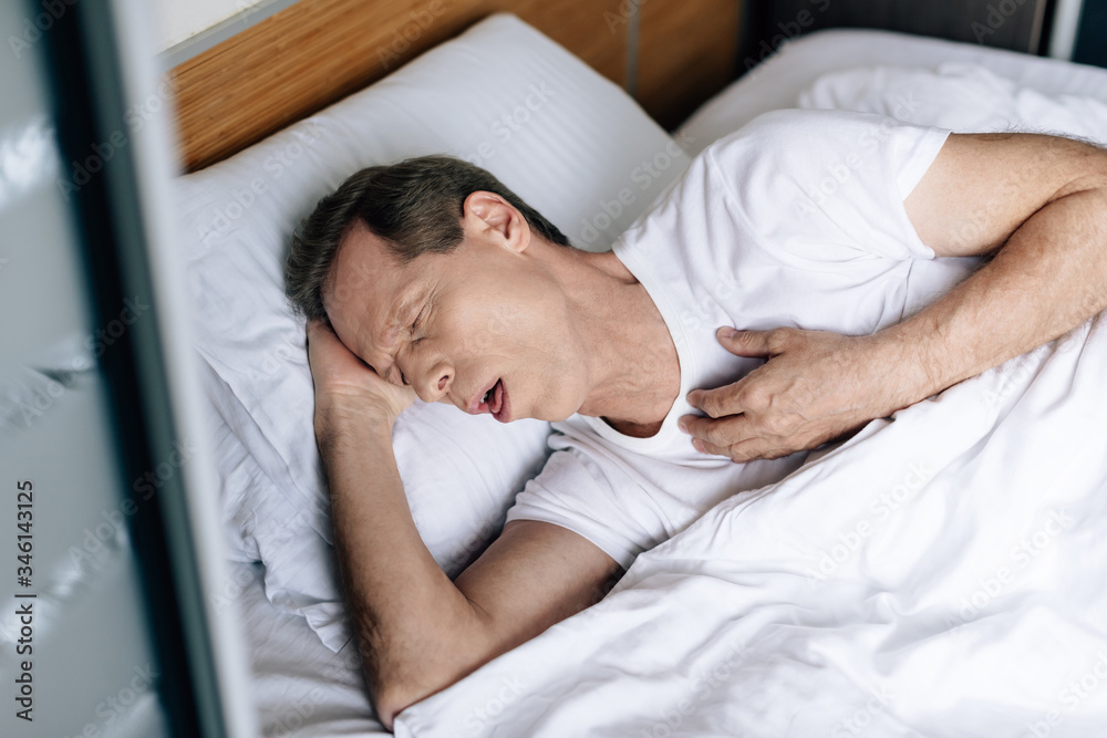 Wall mural overhead view of sick man coughing while lying on bed