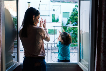 mother and daughter clapping from the window of the house