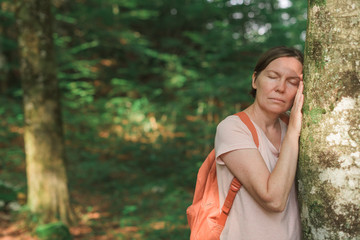 Female environmentalist leaning on tree trunk