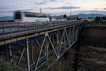 Corinth Canal old bridge with a fast driving bus creating a motion blur effect in early evening