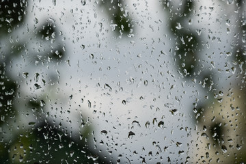 Raindrops on window pane. Blurred background outside the window in the rain.