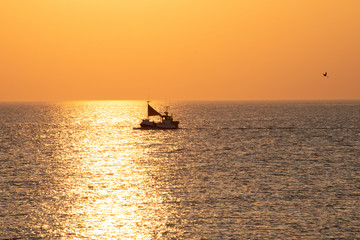 Fischerboot bei der Arbeit, Sonnenuntergang, orange-rot