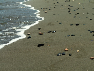 Wet sand on sea beach with pebbles and footprints  