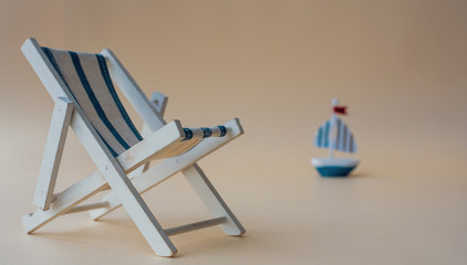 An empty chaise longue and a boat on the horizon. Summer concept, tourism, pandemic, coronavirus,...
