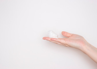Foam for washing on the palm of the hand on a light background. Free space for text. Cleanser, facial cleansing, skin care.