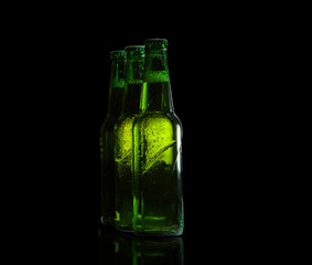 Green glass beer bottles on a black background.