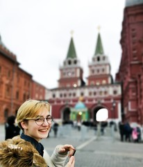 Teen girl with glasses smiling on a background of sights of Moscow, the entrance to Red Square.