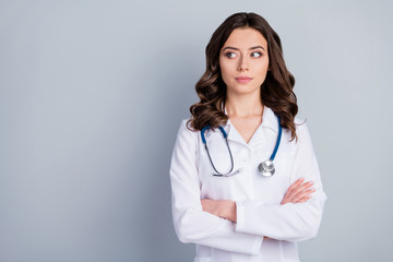 Photo of attractive family doc lady arms crossed patients consultation not smiling virology clinic look side empty space wear white lab coat stethoscope isolated grey color background