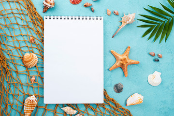 Fototapeta na wymiar Notebook with starfish beside and shells. Summer concept.