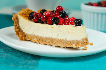New York style Cheesecake on white plate decorated with fresh berries, on table with copy space so sweet and delicious. Homemade bakery concept.