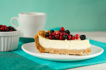New York style Cheesecake on white plate decorated with fresh berries, on table with copy space so sweet and delicious. Homemade bakery concept.