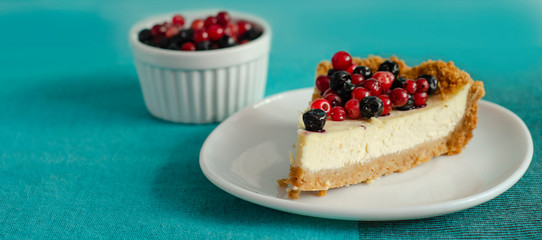 New York style Cheesecake on white plate decorated with fresh berries, on table with copy space so sweet and delicious. Homemade bakery concept.