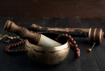 Tibetan singing copper bowl with a wooden clapper on a brown wooden table, objects for meditation...