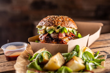 Tasty homemade burger takeaway in a box of recycled paper on wooden boards