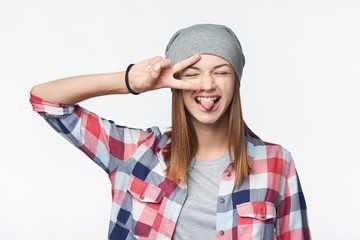 Closeup of funky teen girlshowing peace sign and her tongue