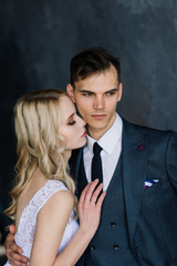 Cute wedding couple in the interior of a classic studio decorated. They kiss and hug each other.