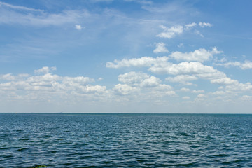 Wide open shot of a calm ocean with cloudy blue sky on Florida coast