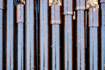 Texture oil drill pipe. Rusty drill pipes were drilled in the well section. Downhole drilling rig.  View of the shell of drill pipes laid in courtyard of the oil and gas warehouse