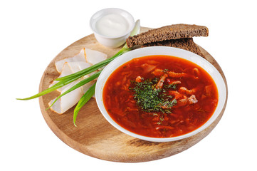 Borscht with sour cream, green onions, bacon and rye bread on a round wooden Board on white background
